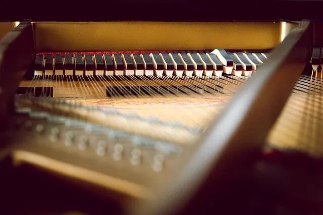 Interior de un piano de cola, con las cuerdas, la mecánica y el paño rojo